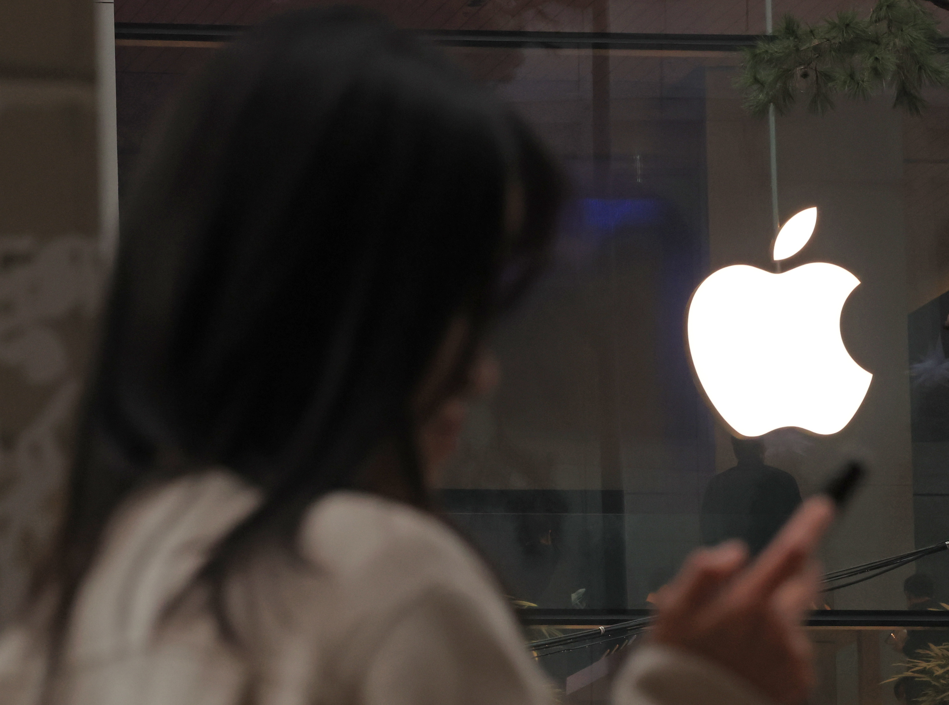 Una mujer usa su iphone frente a una tienda Apple en Se