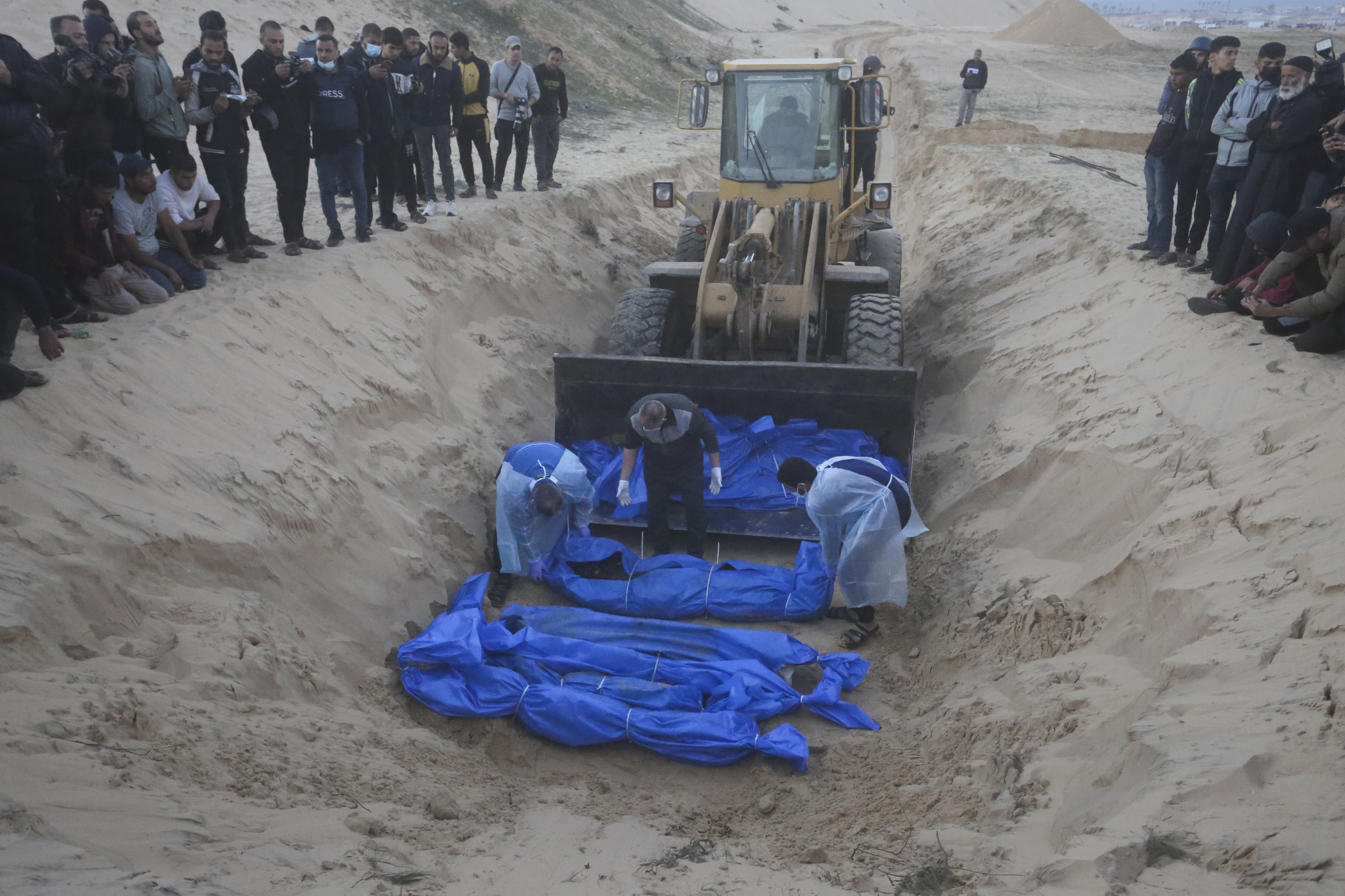 Una excavadora descarga ayer los cuerpos de palestinos asesinados en el norte de Gaza y entregados por el ejrcito israel durante un funeral multitudinario en Rafah.