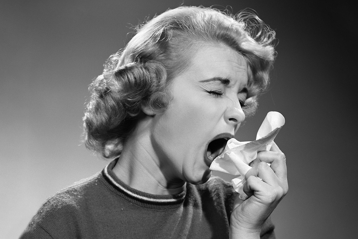 Retrato de una mujer tapándose la boca antes de estornudar, años '50.