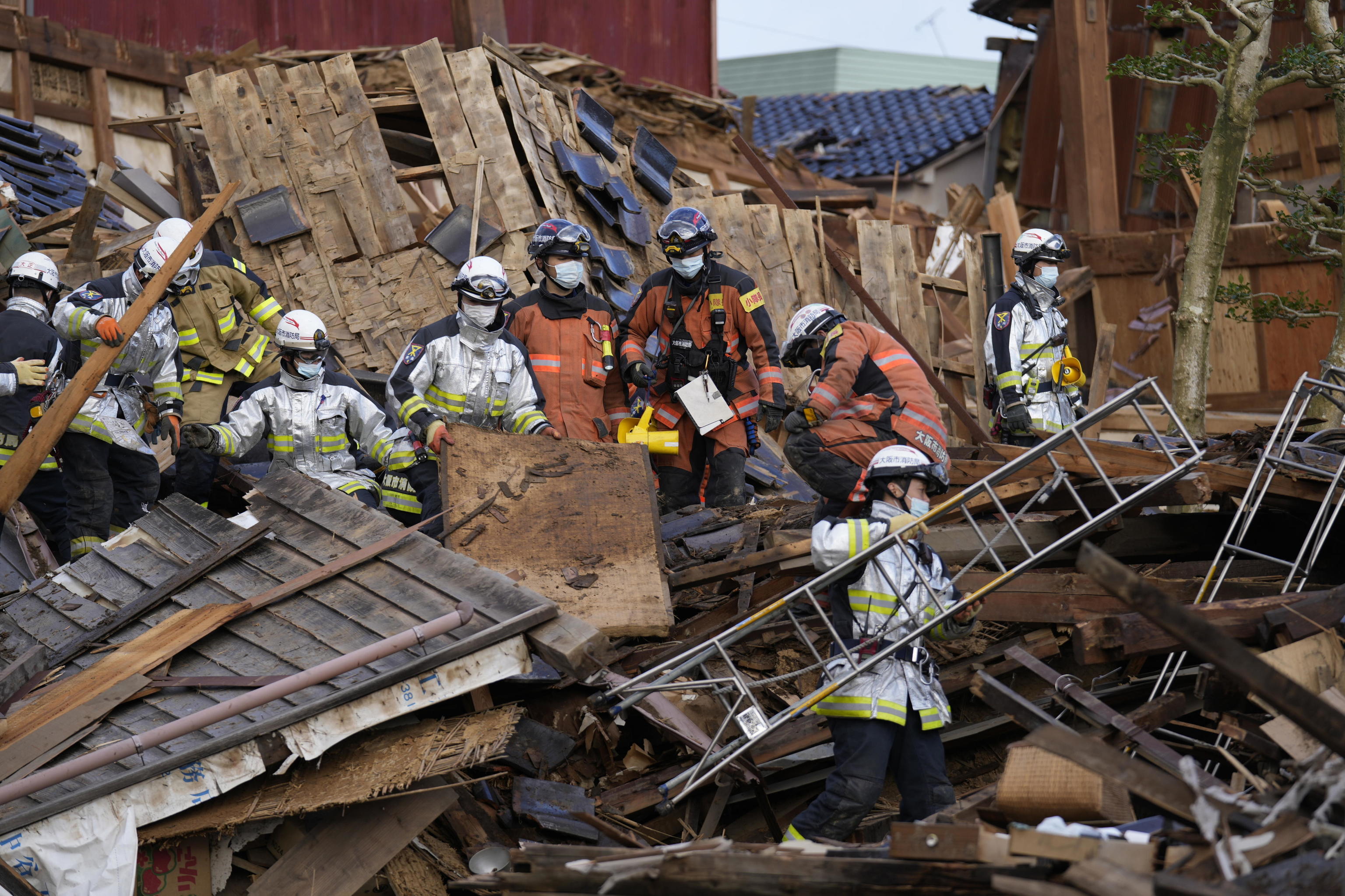 Miembros de emergencias intentan rescatar supervivientes en una casa derrumbada en Wajima.