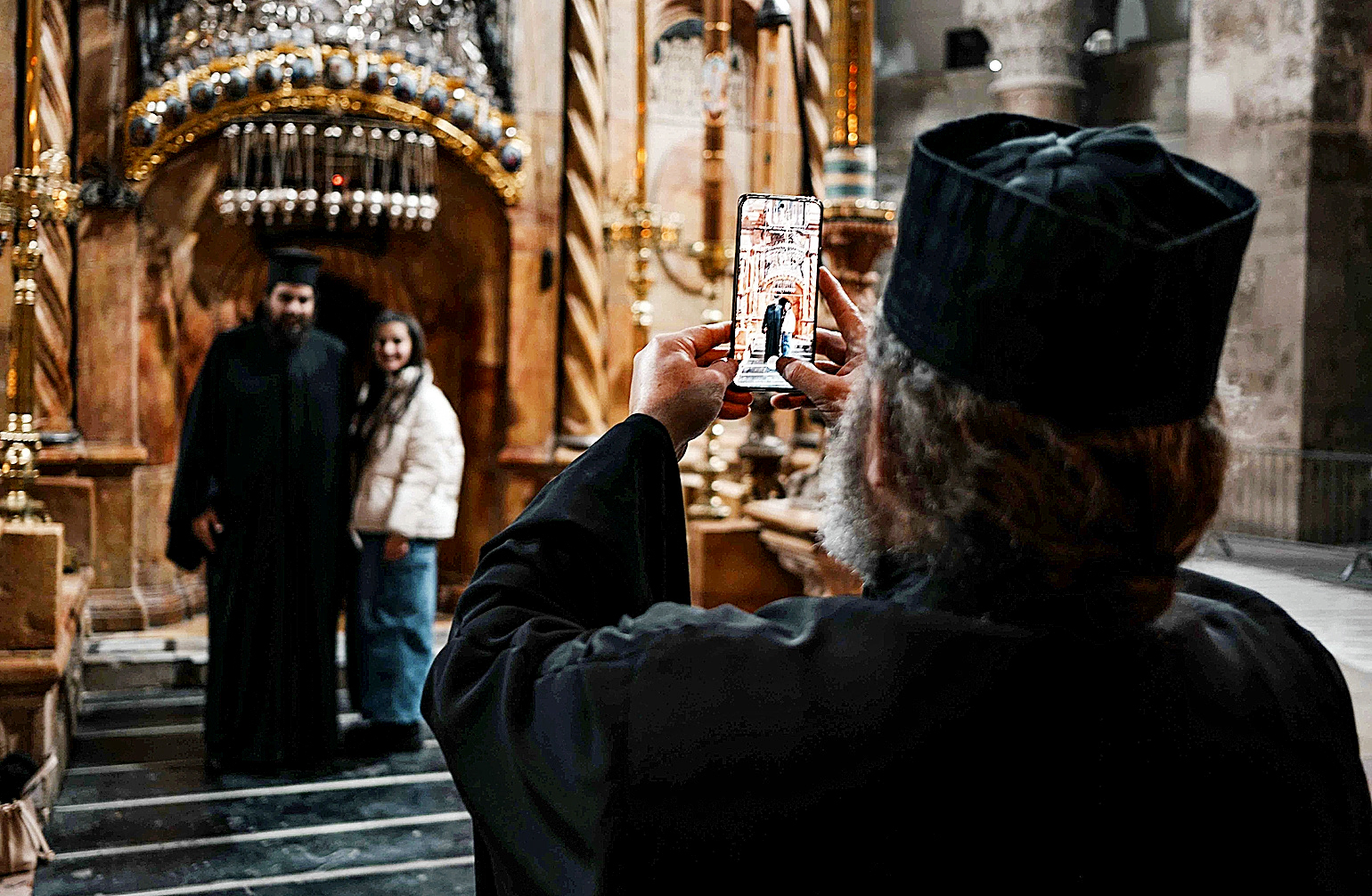 Un sacerdote ortodoxo fotografa a una pareja en uno de los edificios religiosos de la Ciudad Vieja de Jerusaln.