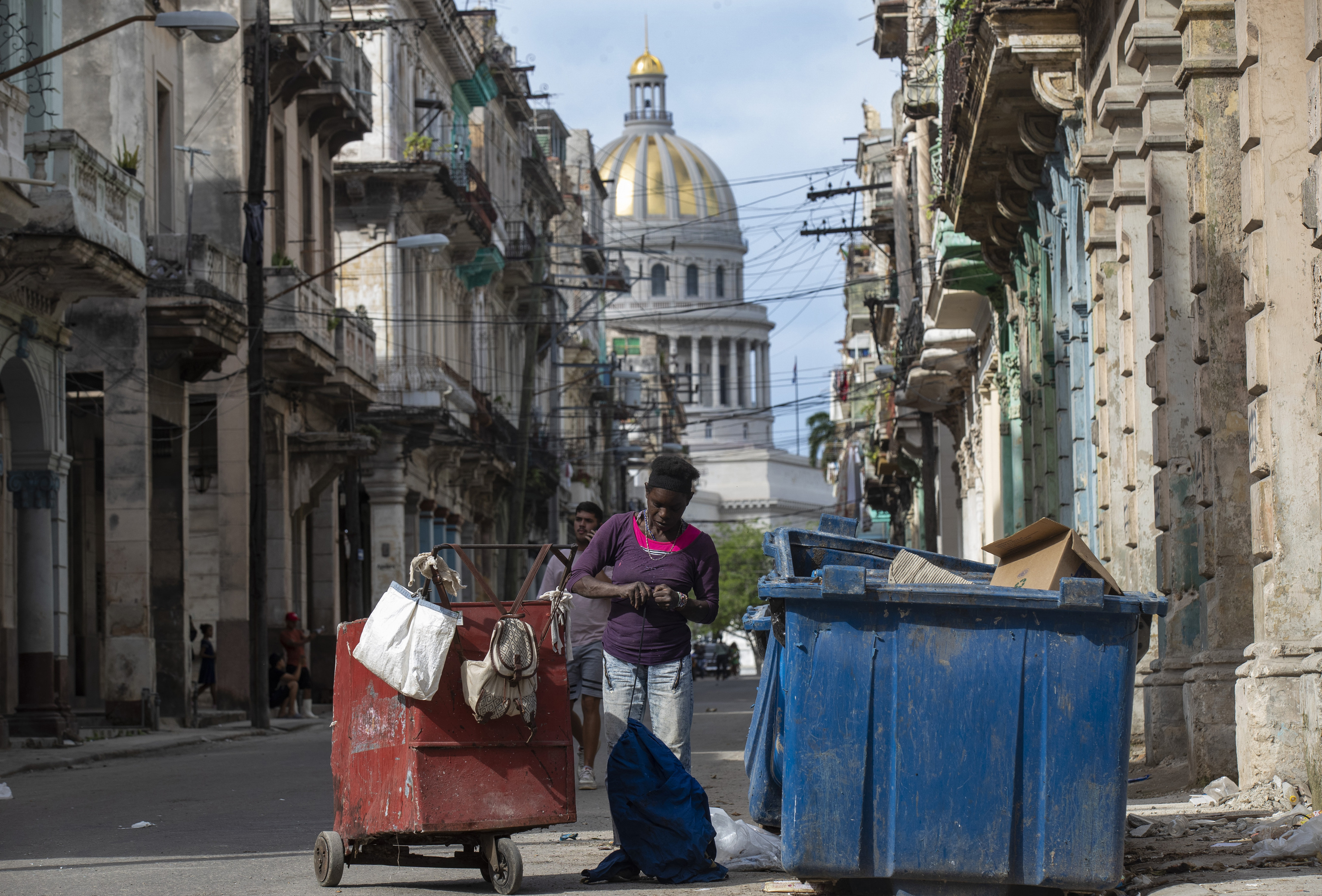 Una mujer busca algo de valor en la basura cerca del Capitolio de La Habana.