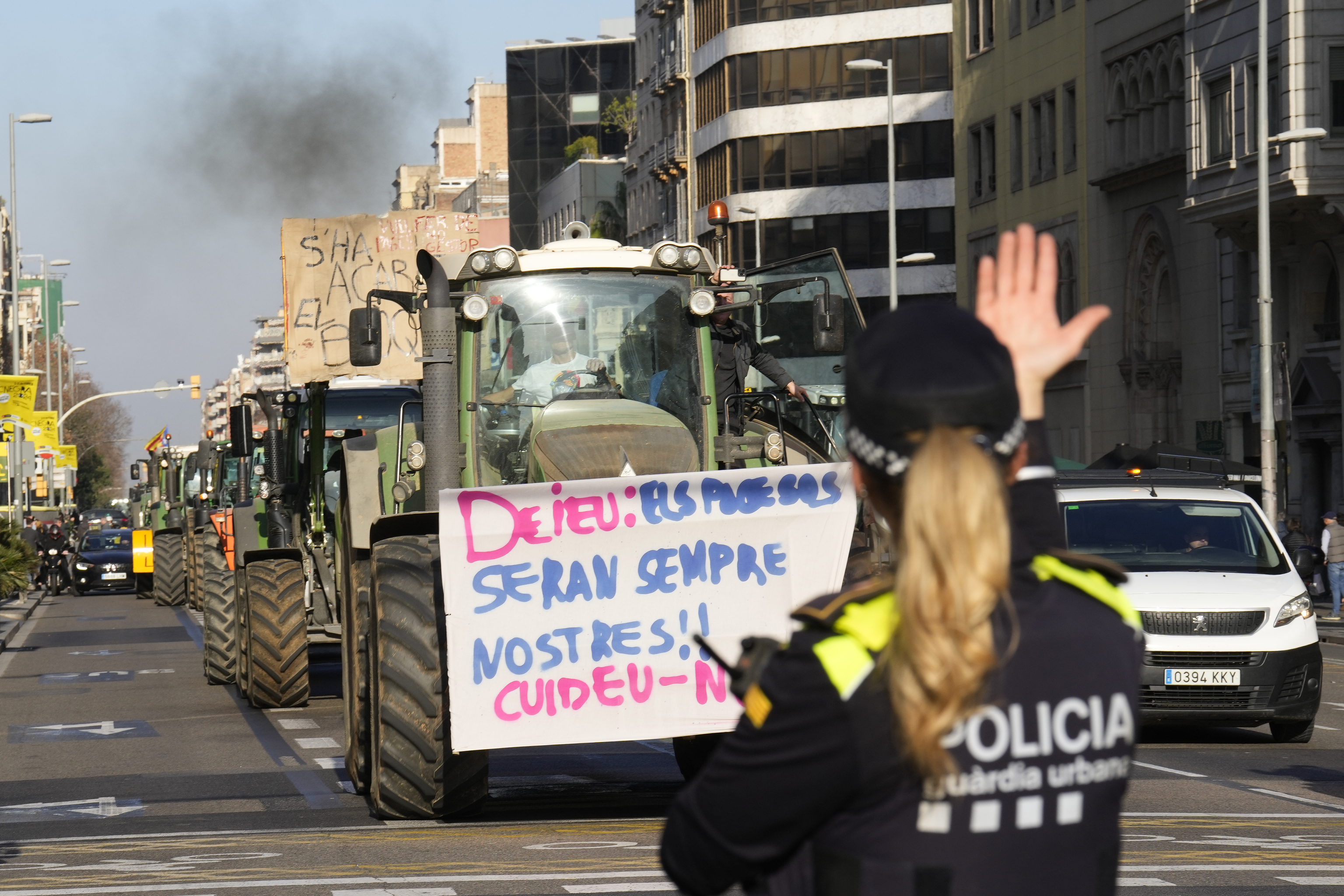 Una agente de la Guardia Urbana de Barcelona ordena el trfico ante la llegada de los tractores a la calle Aragn, en el centro de la ciudad.