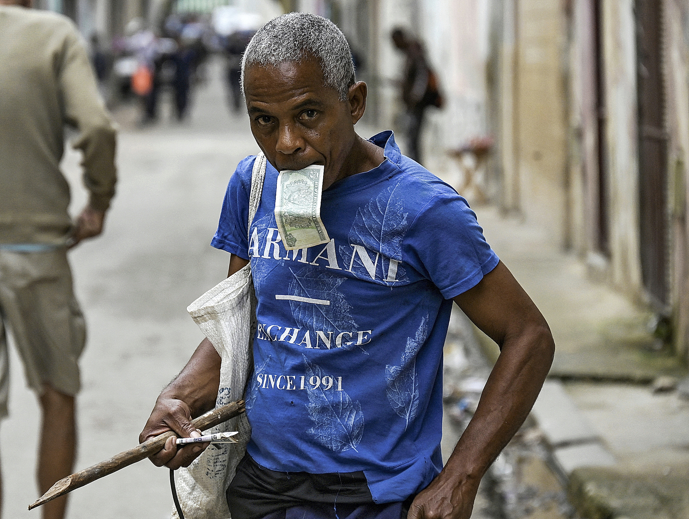 Un hombre sostiene un billete en la boca en una calle de La Habana.