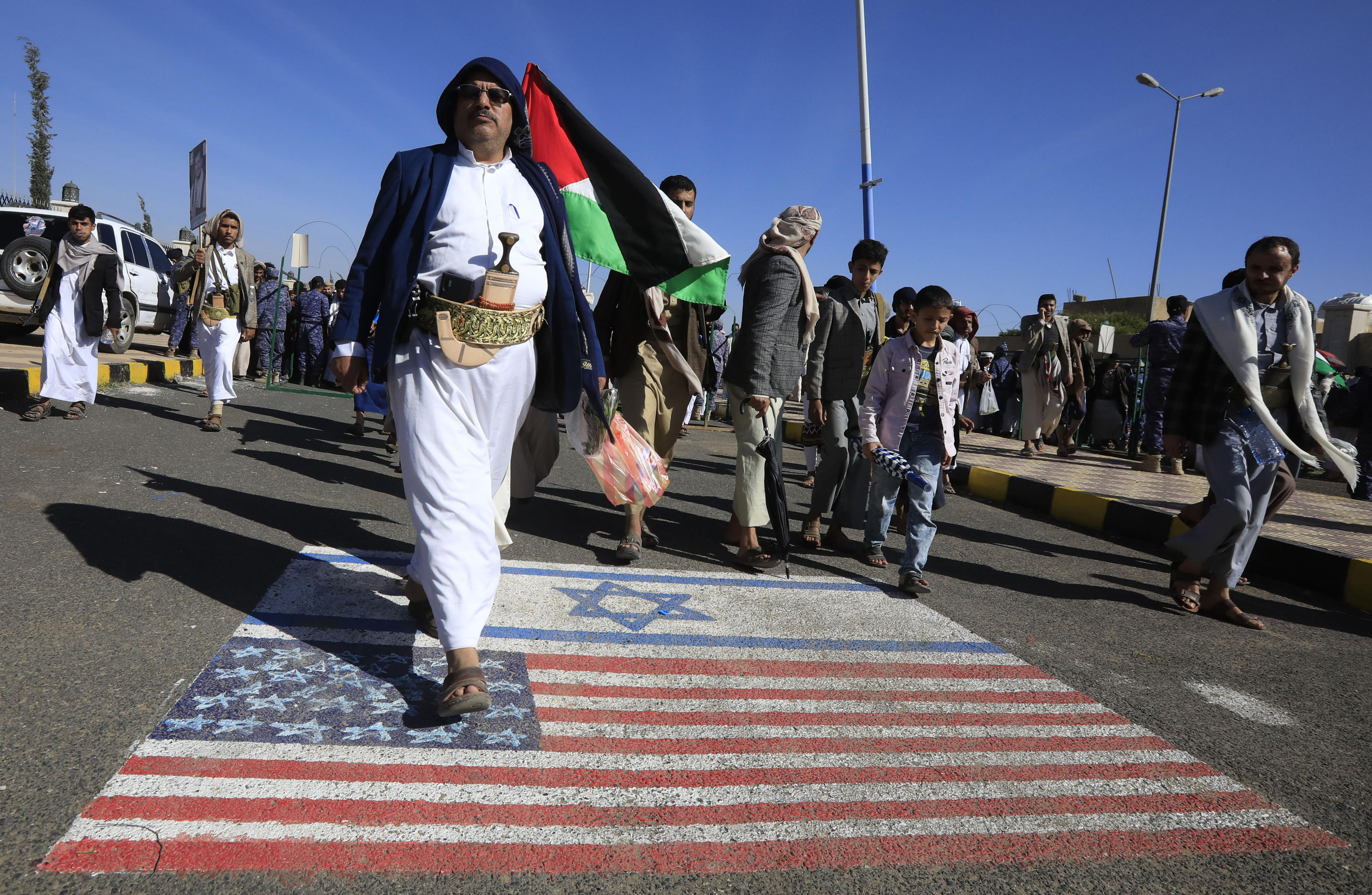 Houthi supporters step on Israeli and US flags in Sana'a.