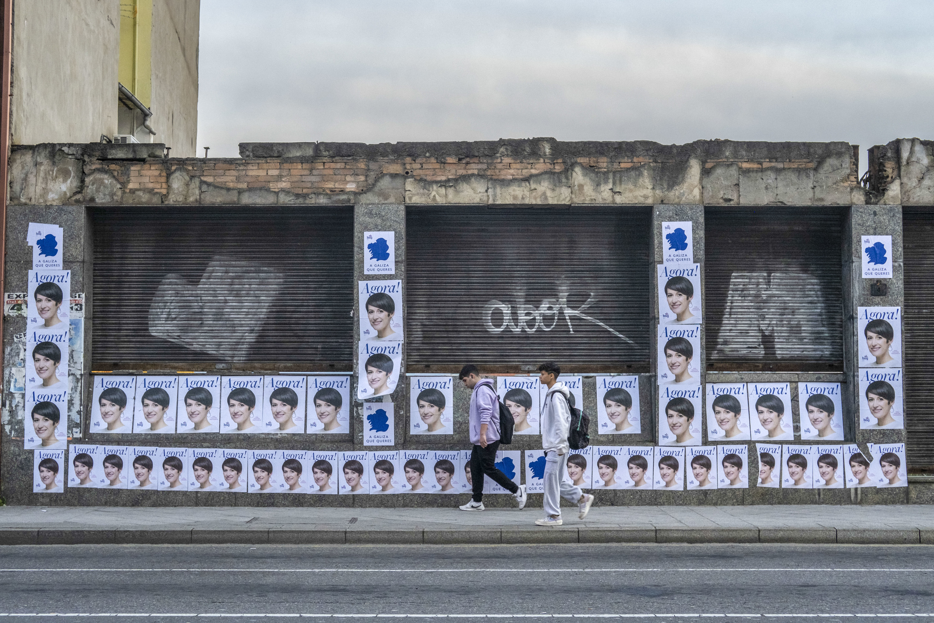Dos jóvenes pasan frente a carteles electorales de la candidata Pontón en Ourense.