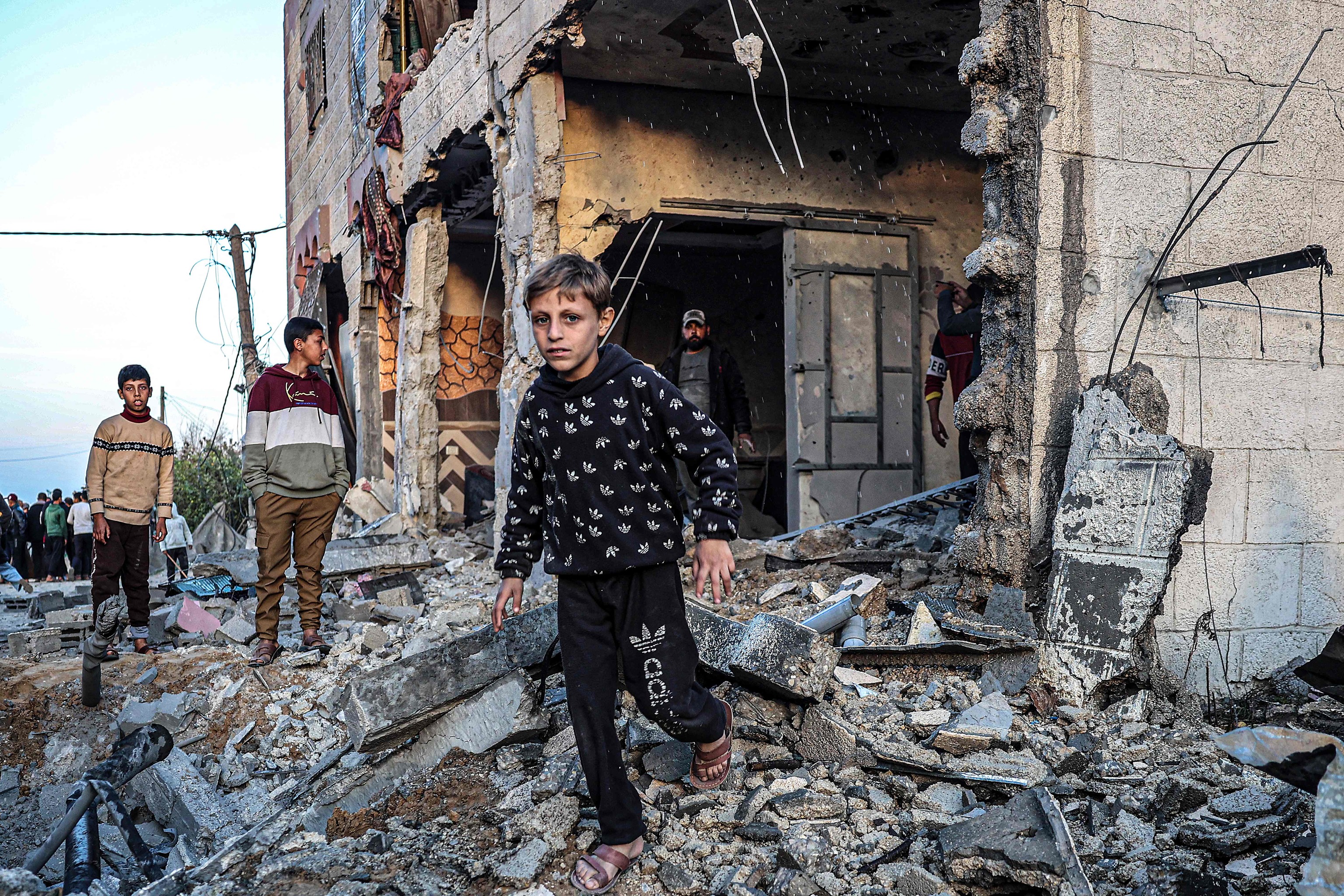 Varias personas caminan sobre escombros en la ciudad de Rafah.