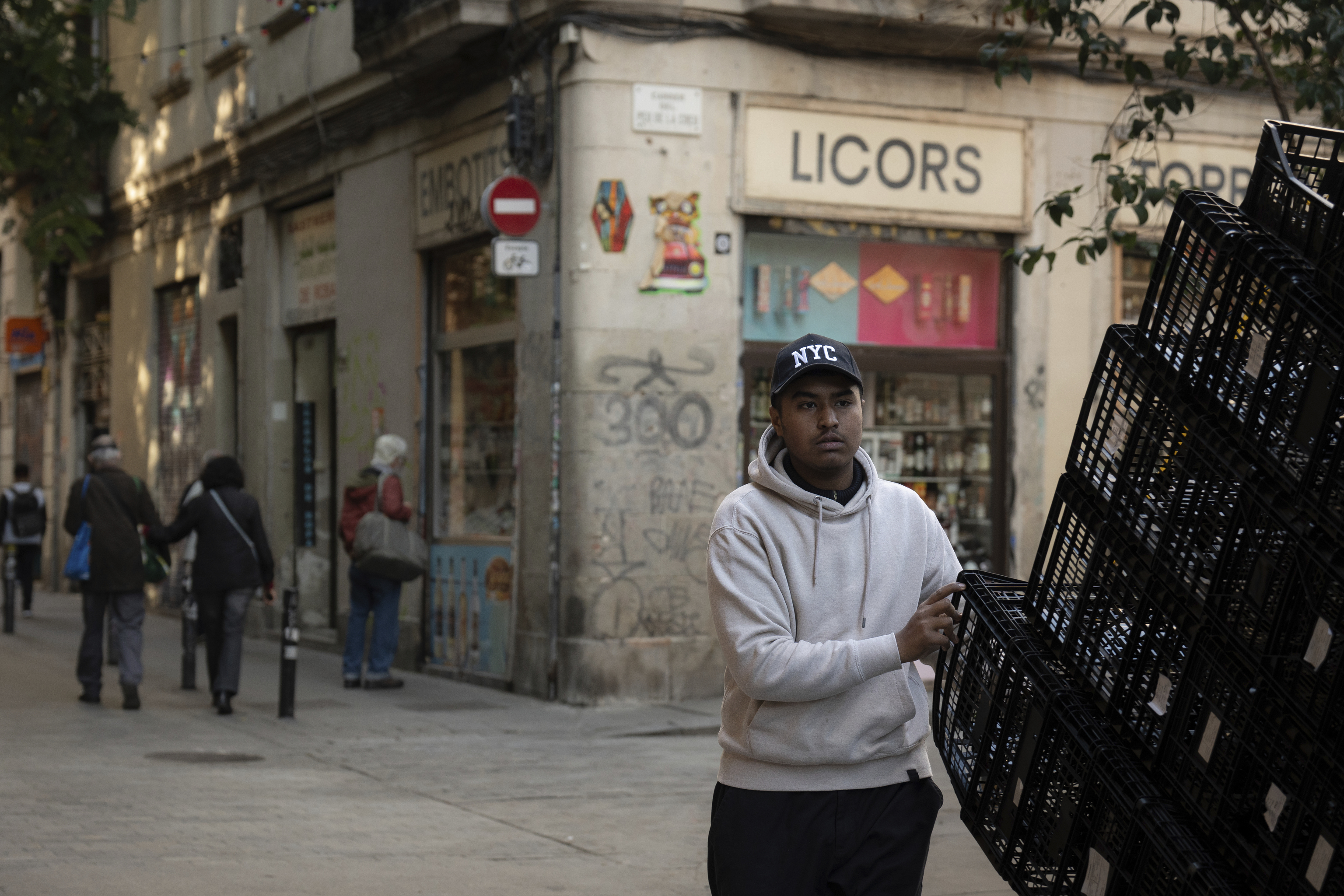Un hombre camina cargado por una calle en Barcelona