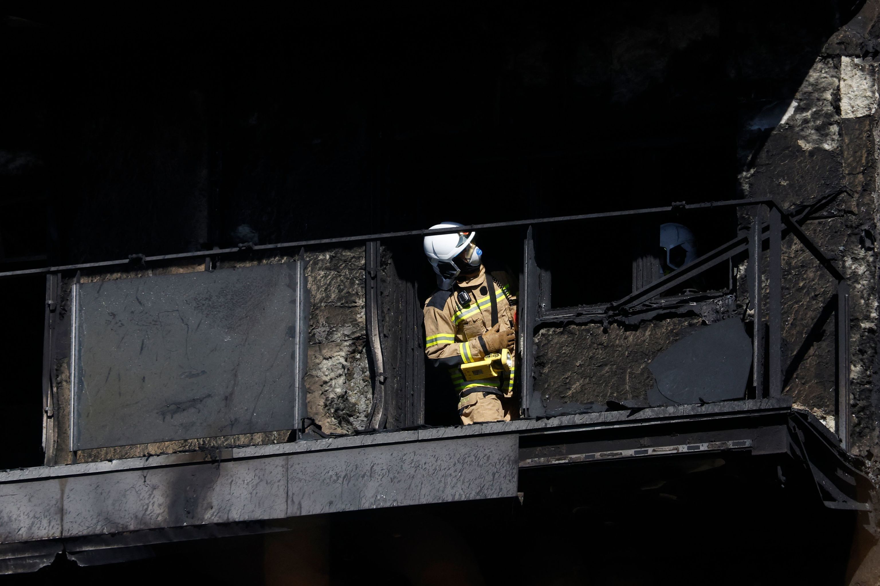 Un bombero inspecciona la terraza de uno de los pisos devastados por el incendio.