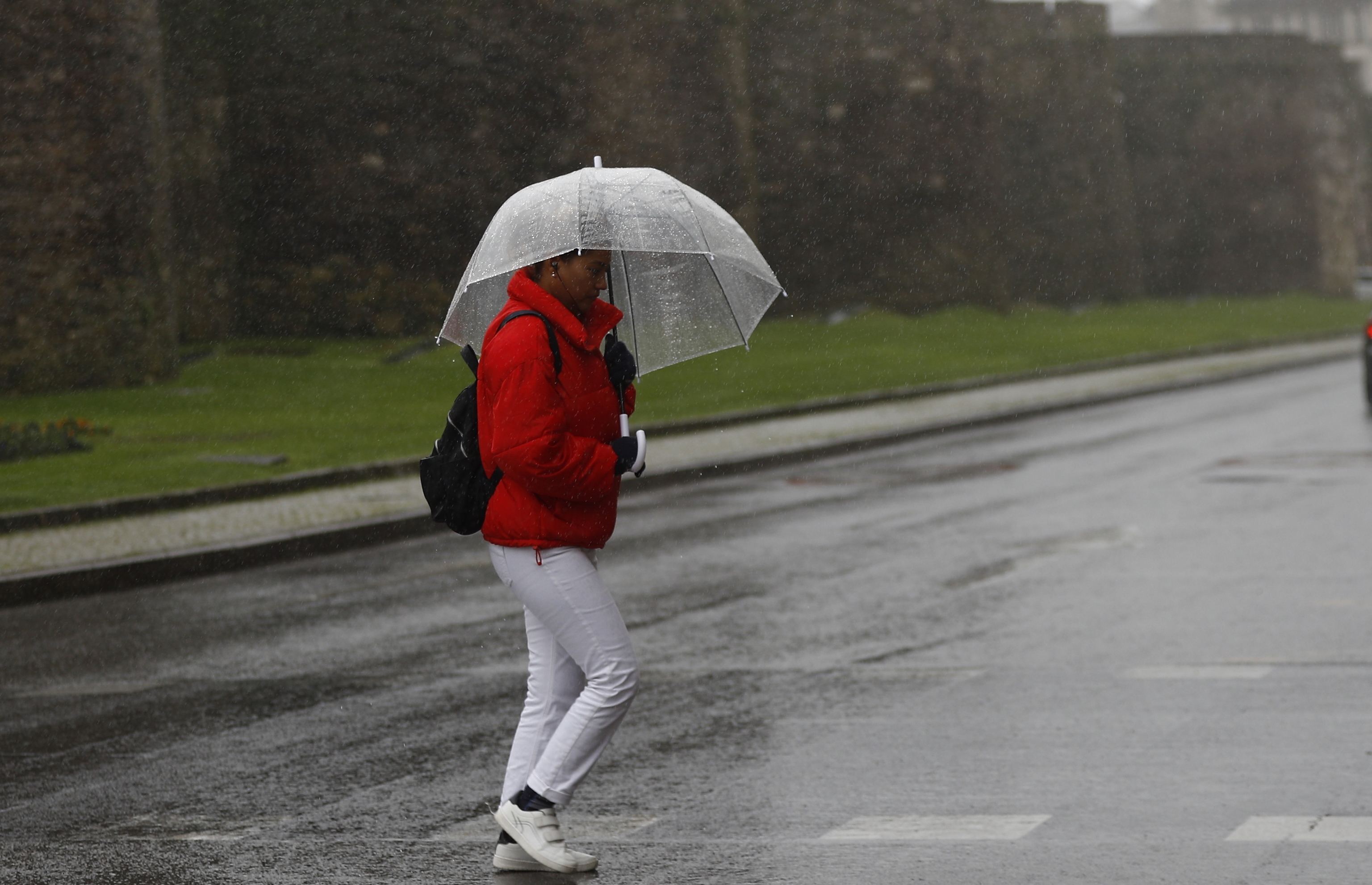 Una persona se protege de la lluvia y el viento en una calle de Lugo.