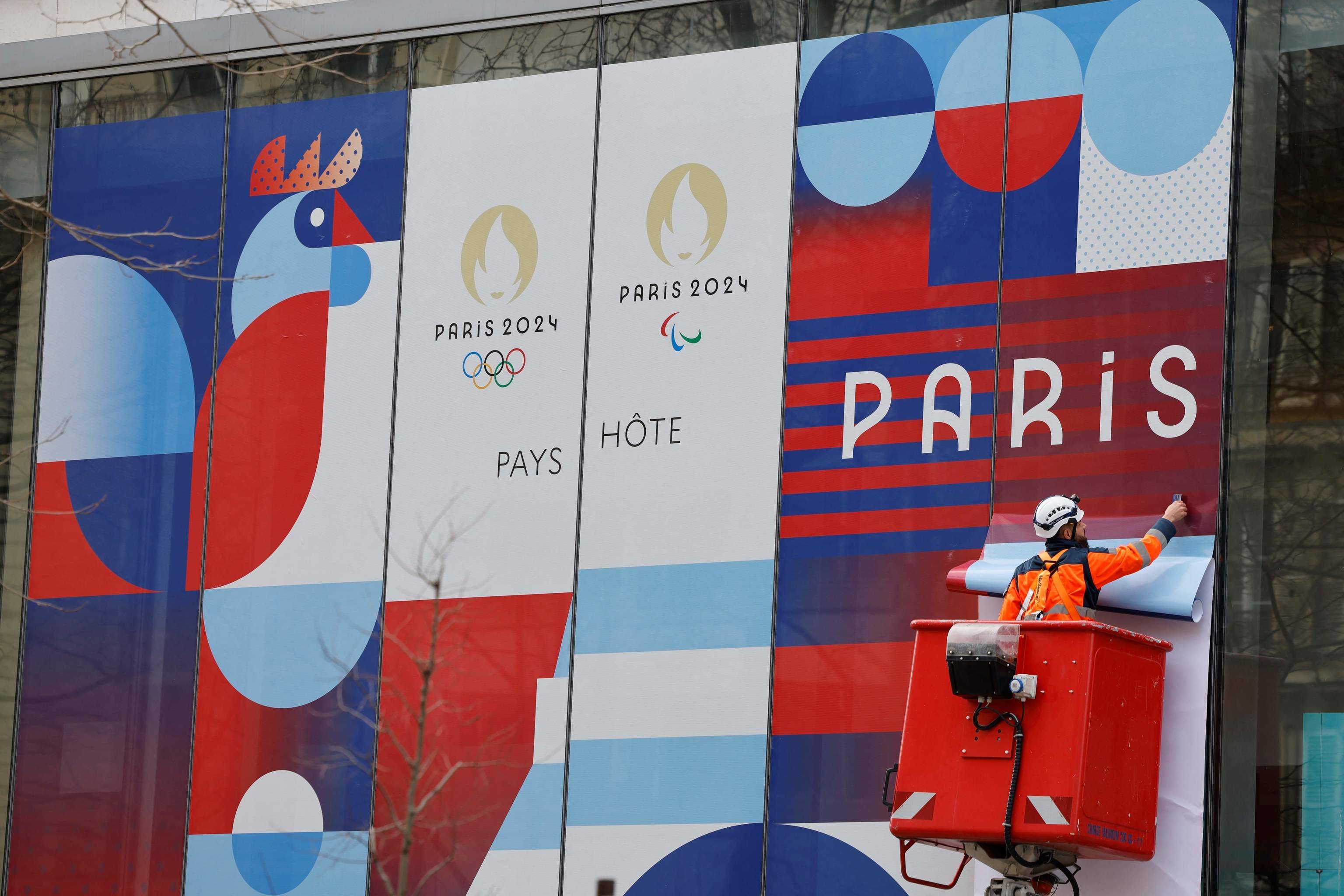 Un operario coloca un cartel de los Juegos Olmpicos en Pars.