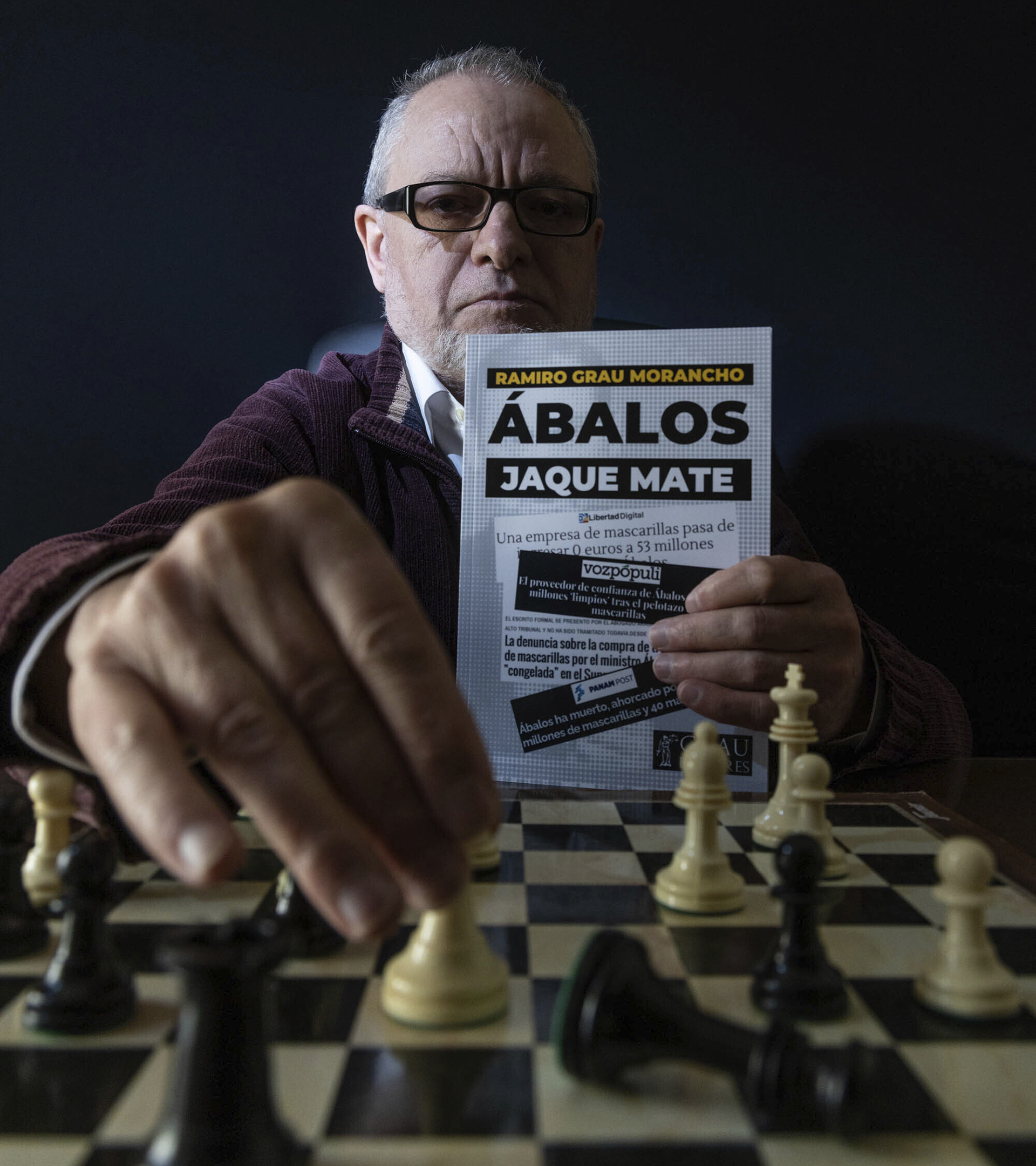 El abogado mao Ramiro Grau, este pasado jueves, realizando un movimiento de ajedrez y sosteniendo su libro 'balos Jaque Mate'.