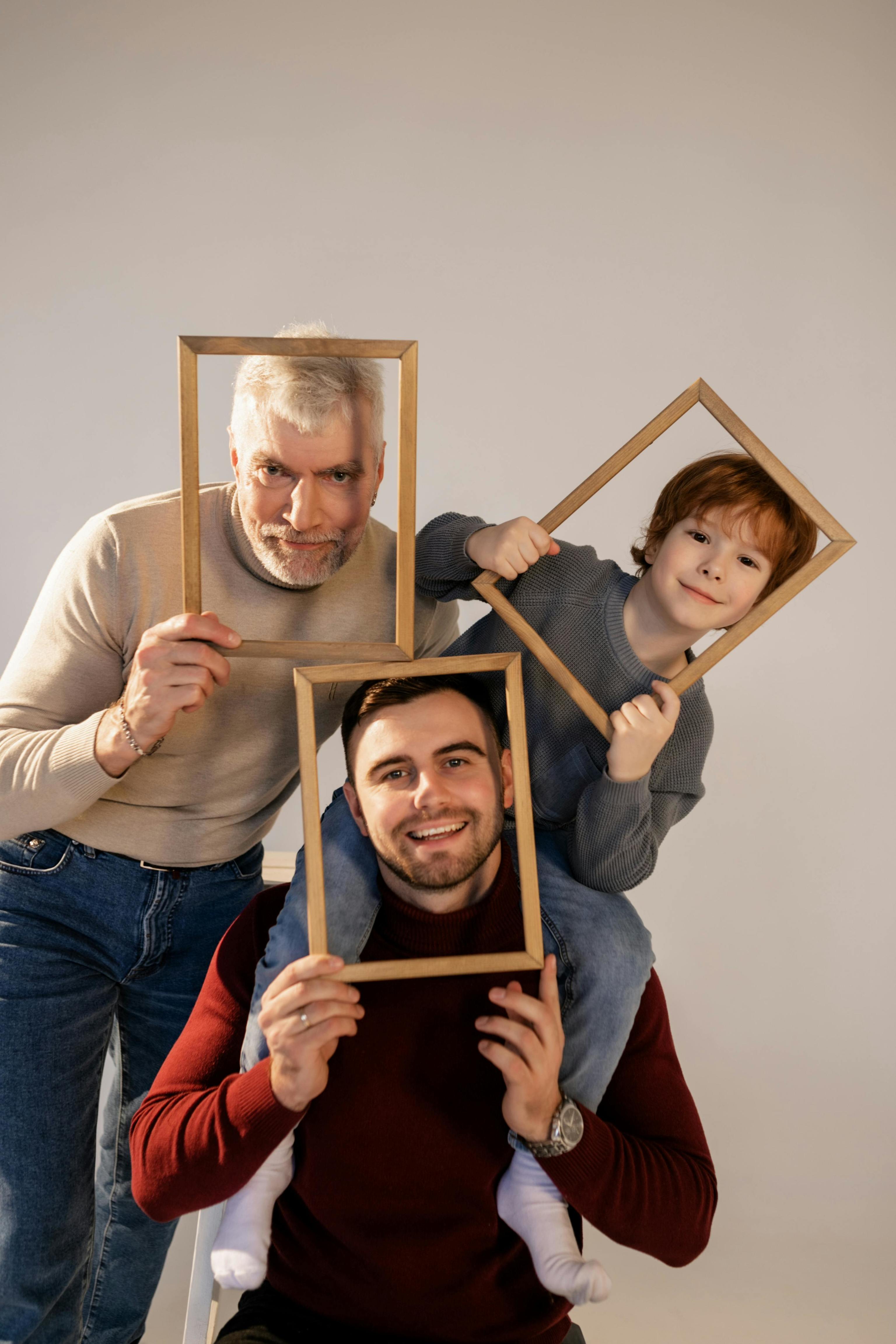 Padre, hijo y nieto, sosteniendo unos marcos.