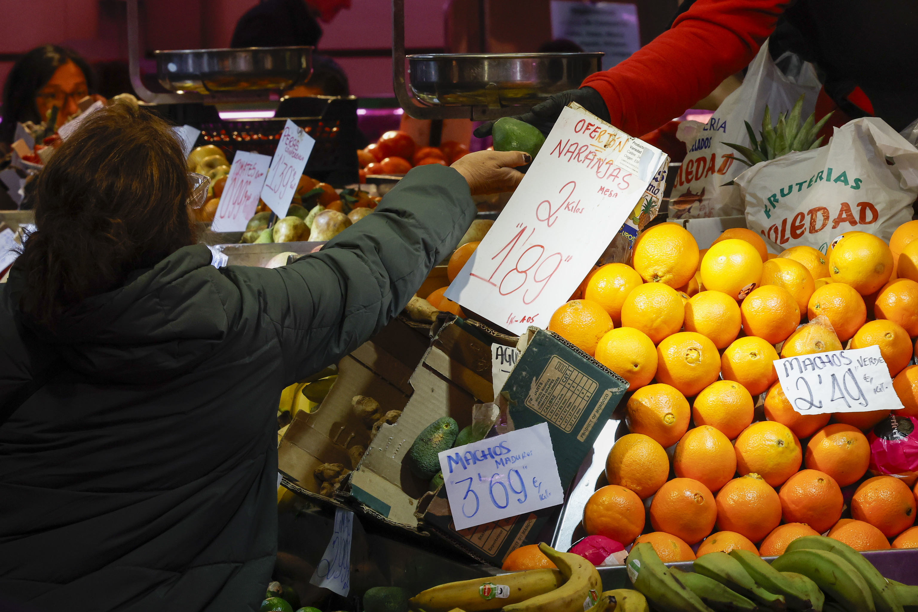 Una consumidora compra en un puesto de frutas y verduras en un mercado de abastos de Madrid