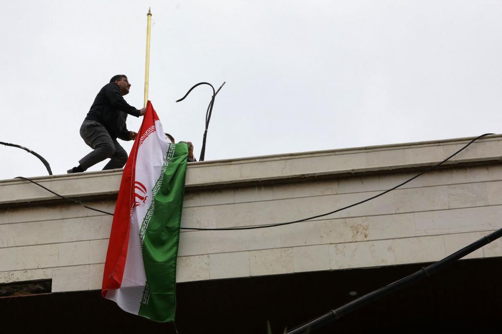 Un hombre coloca la bandera iran en un nuevo anexo consular de la embajada de Irn en Damasco.