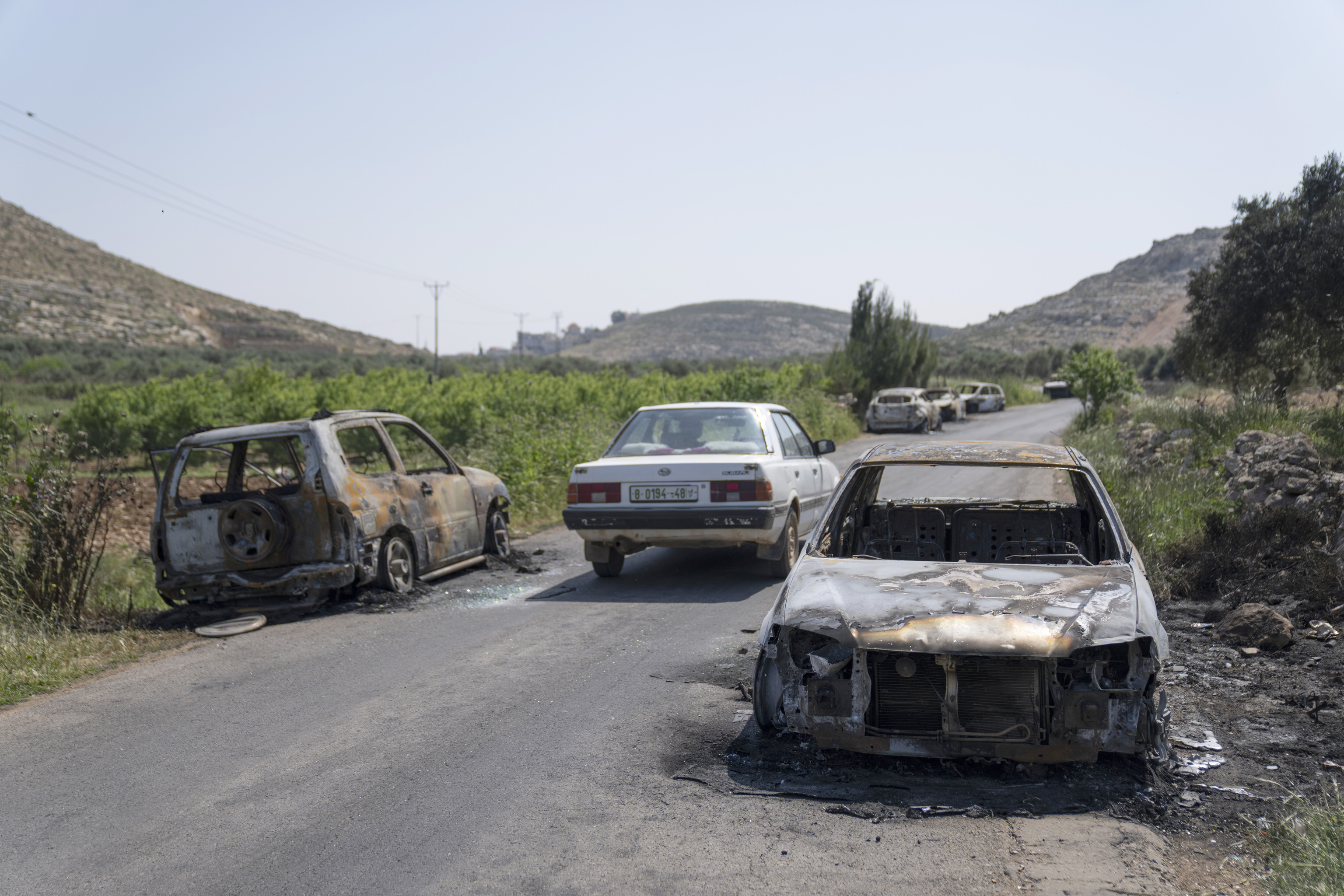 Vehculos calcinados,  a ambos lados de una carretera en la localidad cisjordana de Al Mughayir.