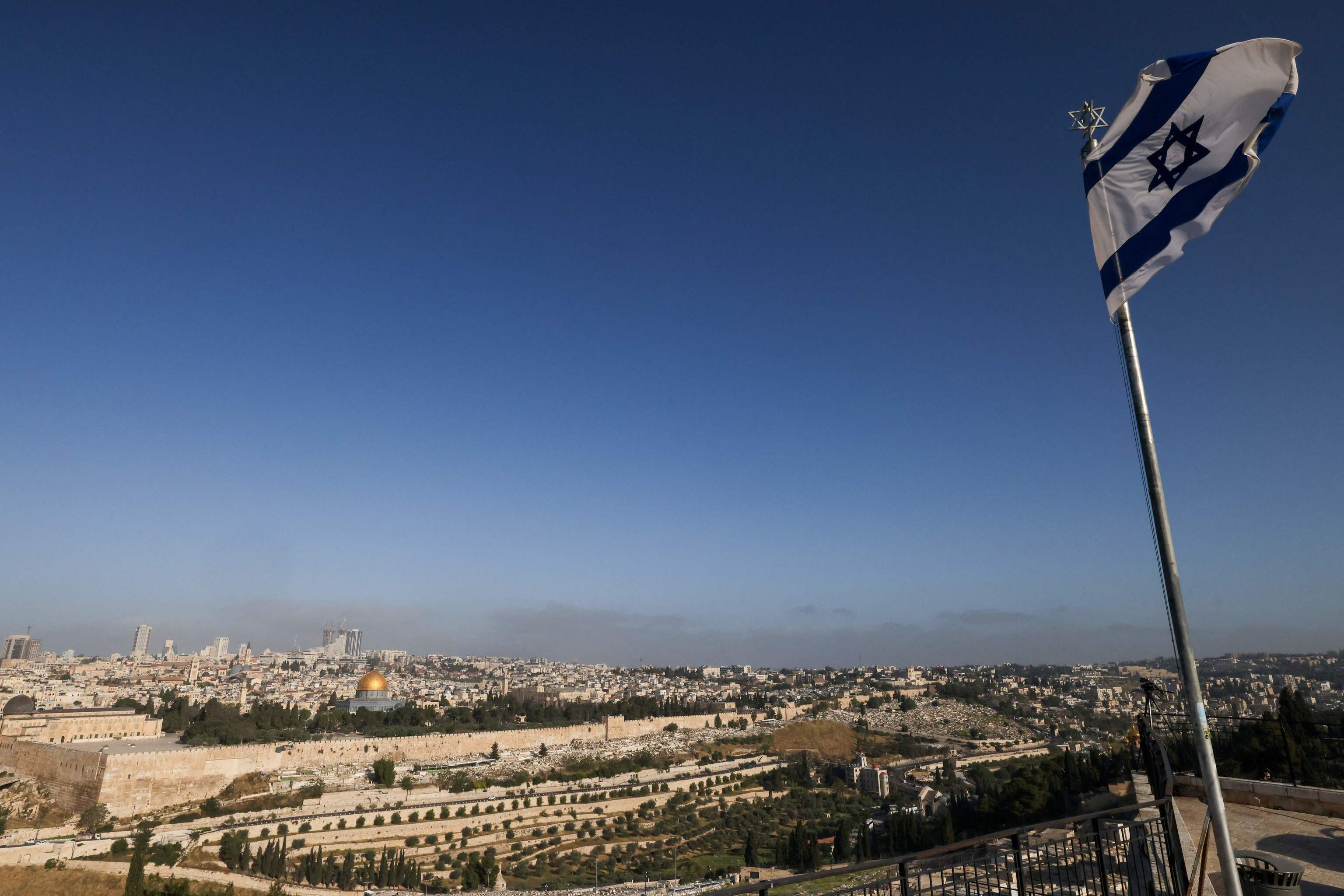 Una bandera israel ondea en el Monte de los Olivos con vistas al complejo de la mezquita de Al Aqsa y al perfil de la ciudad de Jerusaln.