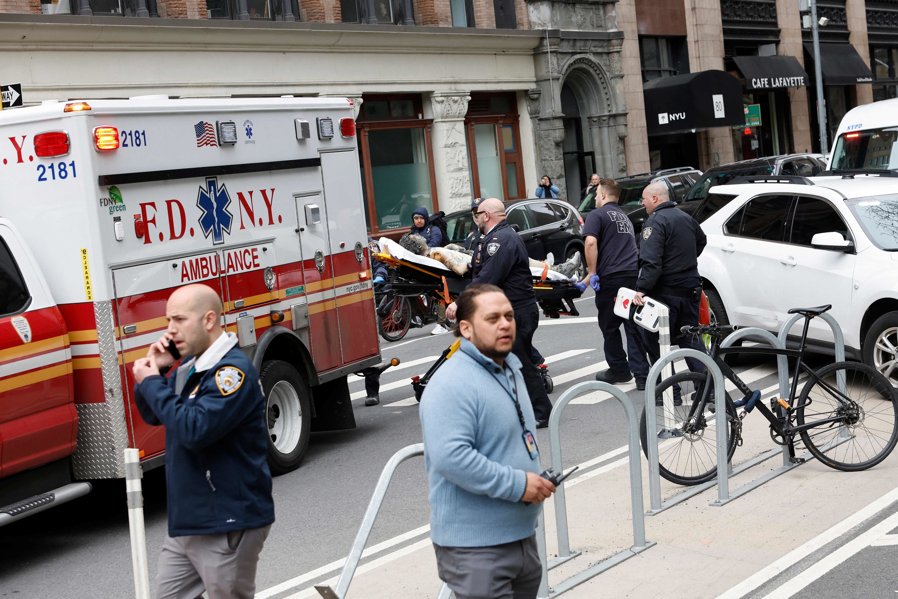 Los servicios de emergencia llevan a la persona que se ha prendido fuego a la ambulancia en una camilla, este viernes en Nueva York, frente a la Corte donde se juzga a Trump.