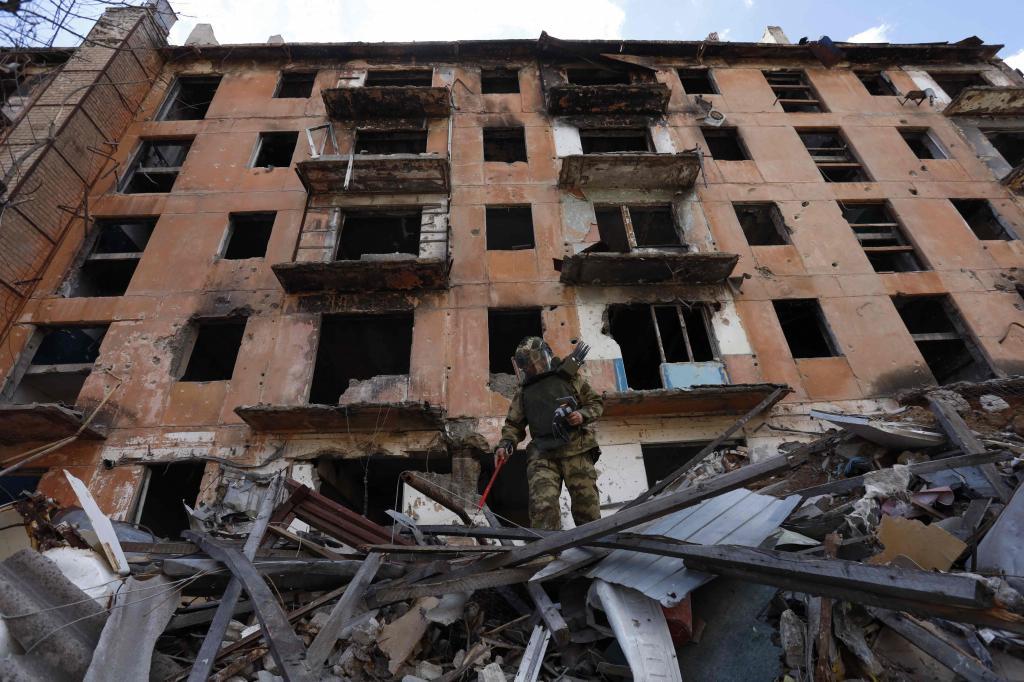Un zapador ruso revisa un edificio en ruinas en Mariupol, en la Ucrania controlada por Rusia.
