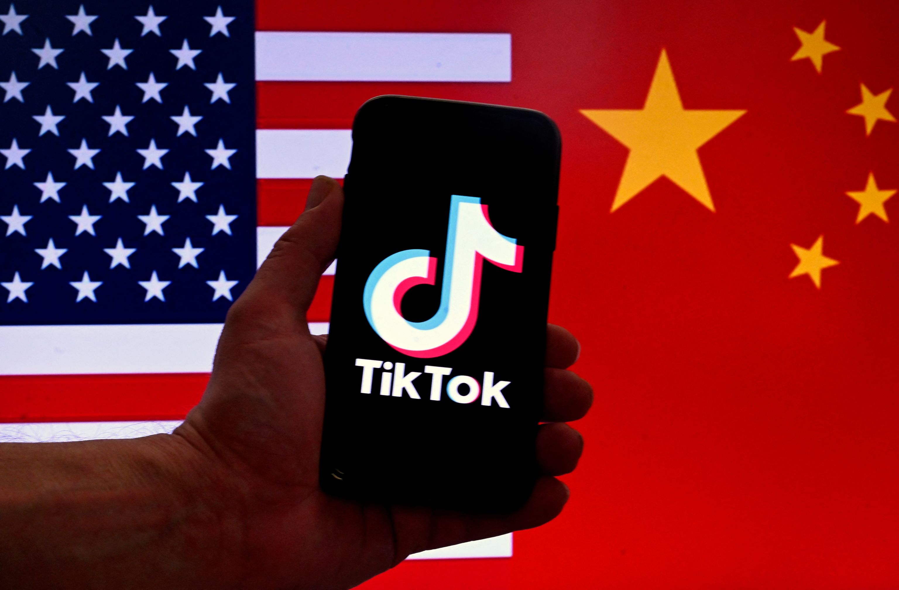 Un telfono con el logo de TikTok ante las banderas de EEUU y China.
