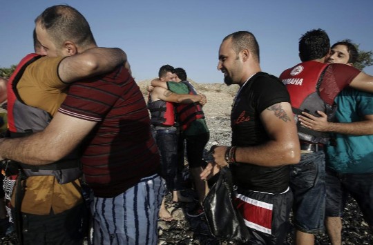 Inmigrantes sirios se abrazan tras llegar en en una lancha a la isla de Kos.