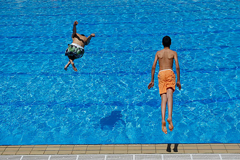 Dos niños se lanzan a la piscina. | Diego Sinova