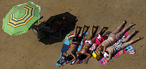 Varias personas toman el sol en Chipiona.| Reuters | Javier Barbancho