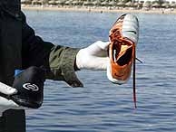 Un miembro de los equipos de rescate muestra dos zapatillas. (EPA)