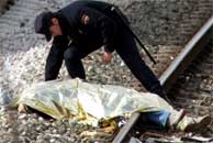 Un policía cubre un cadaver en las vías de la estación de Santa Eugenia (EFE).