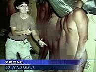 Una soldado seala a un prisionero desnudo. (CBS)