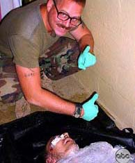 Graner, uno de los soldados que estn siendo juzgados, sonriente junto a un preso muerto.