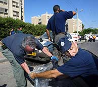 Dos agentes recogen parte del cohete lanzado por Hamas en Sderot. (AFP)