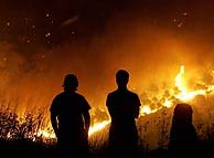 Dos hombres contemplan el incendio del parque. (EFE)