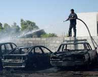 Un voluntario apaga las llamas de algunos coches afectados en el atentado de Bagdad. (AP)