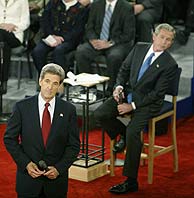 Kerry habla durante el debate mientras Bush atiende al discurso de su rival en el fondo de la imagen. (AFP)
