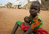 Una nia, con su hermana en brazos y la mirada entristecida, en el campo de Krinding. (AFP)