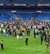Los espectadores salen del Bernabéu por el terreno de juego. (Foto: AP)VEA LA SECUENCIA EN IMÁGENES