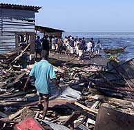 Un grupo de personas observa los destrozos del maremoto en una playa de Colombo. (Foto: AP)