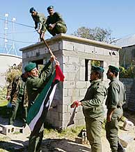 Miembros de la seguridad palestina izan una bandera en un puesto de control. (Foto: Reuters)