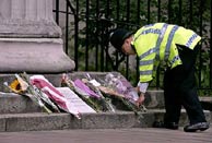 Un policía deposita flores por las víctimas del 7-J. (Foto: AP)