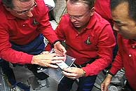 Tres de los astronautas examinan los fragmentos de aislante sacados de la panza del Discovery ayer. (Foto: NASA)