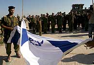 Soldados israeles doblan su bandera durante una ceremonia en el que fuera asentamiento de Netzarim. (Foto: EFE)