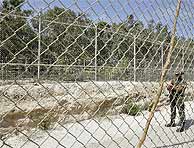 Una soldado vigila la doble valla de Melilla. (EFE)