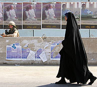 Una mujer pasea por delante de un soldado y de carteles electorales. (Foto: AFP)