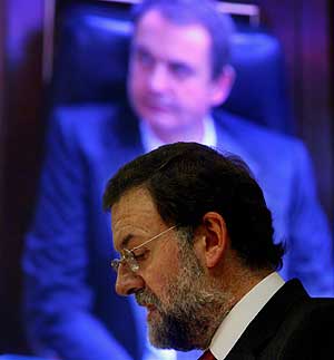 Rajoy habla en la tribuna, delante de una imagen de Zapatero en la pantalla del Congreso. (Foto: REUTERS)