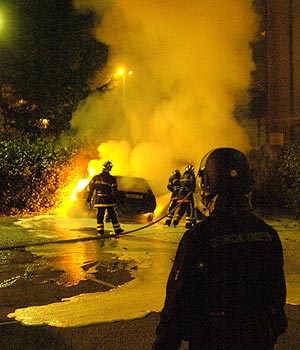 Varios bomberos tratan de apagar un coche en Venissieux, a las afueras de Lyon. (Foto: AP)