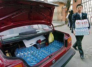 Un hombre lleva botellas de agua al maletero de su coche en Harbin. (Foto: EFE)