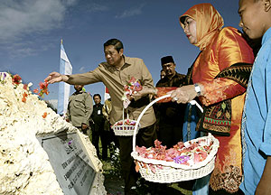 El presidente indonesio y su esposa dejan una ofrenda floral en la fosa comn de Lhok Nga. (AP)