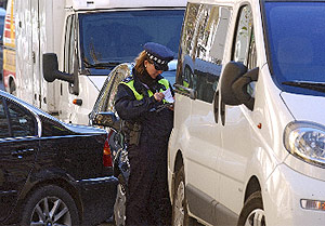 Una polica multa a un coche aparcado en doble fila. (Toledo)