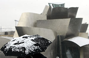 Una persona contempla, con su paraguas cubierto de nieve, el Guggenheim de Bilbao. (Foto: EFE)